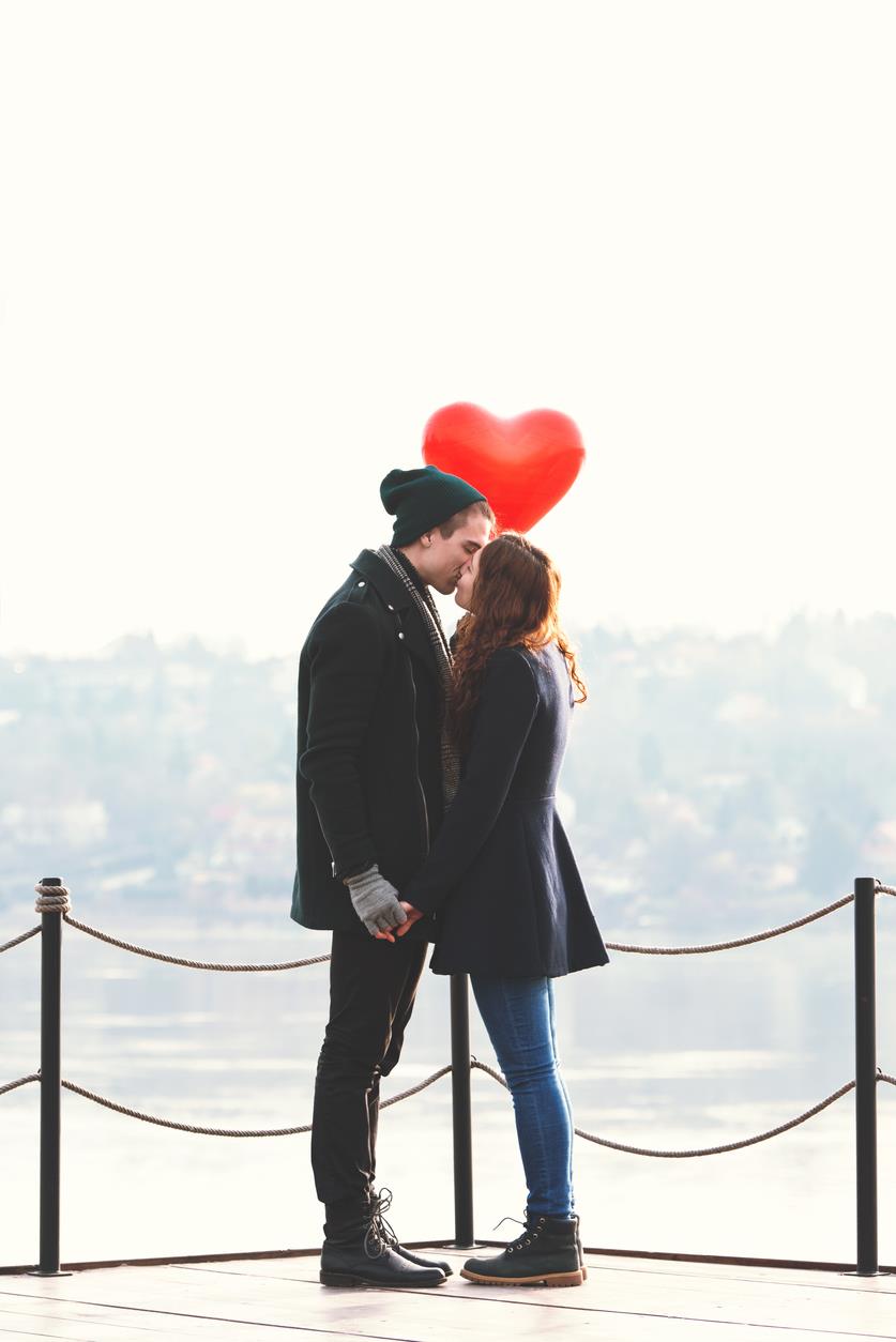 Una giovane coppia si bacia su un pontile