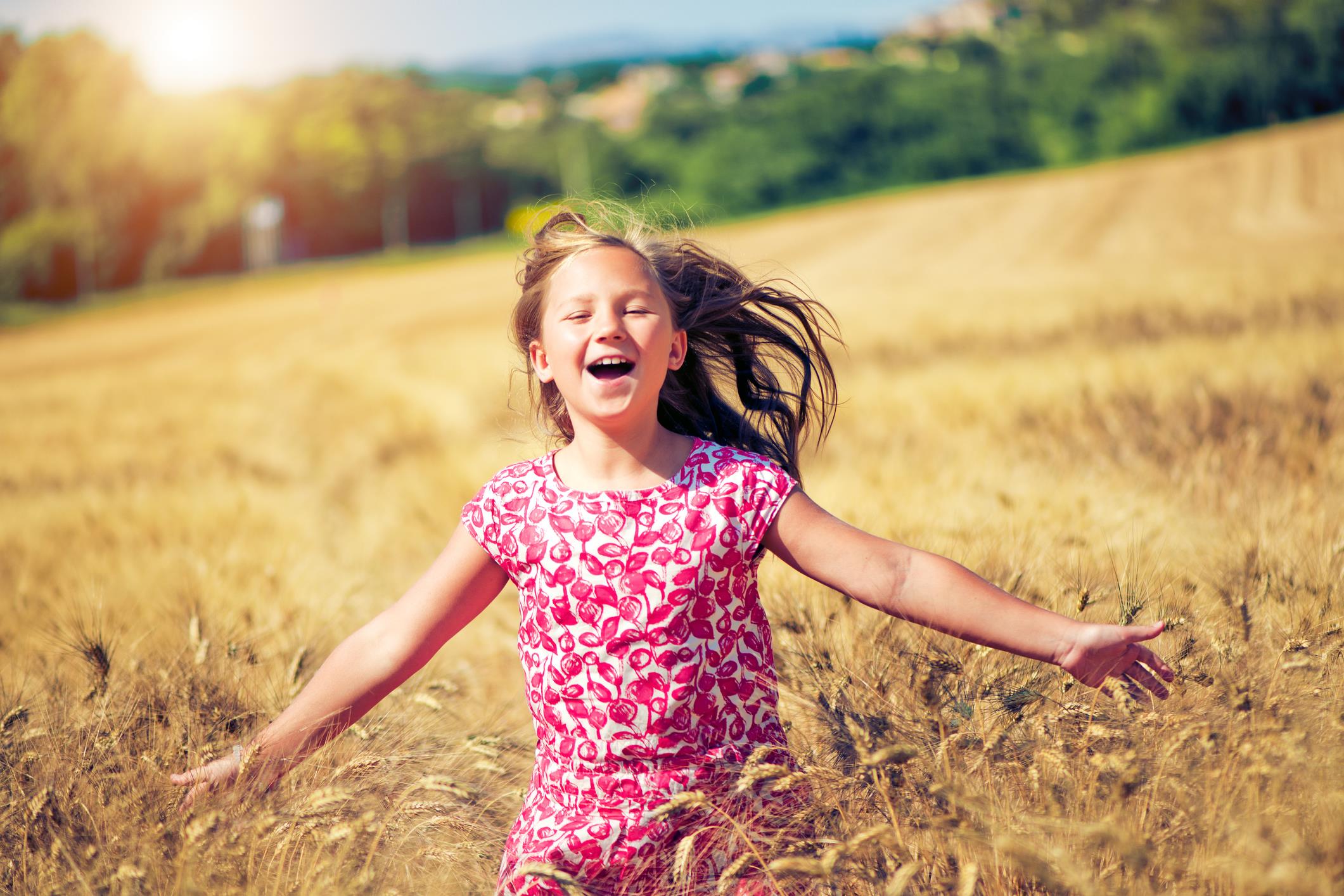 Bambina corre felice in un campo di grano