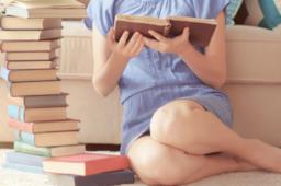 Ragazza legge un libro seduta a terra