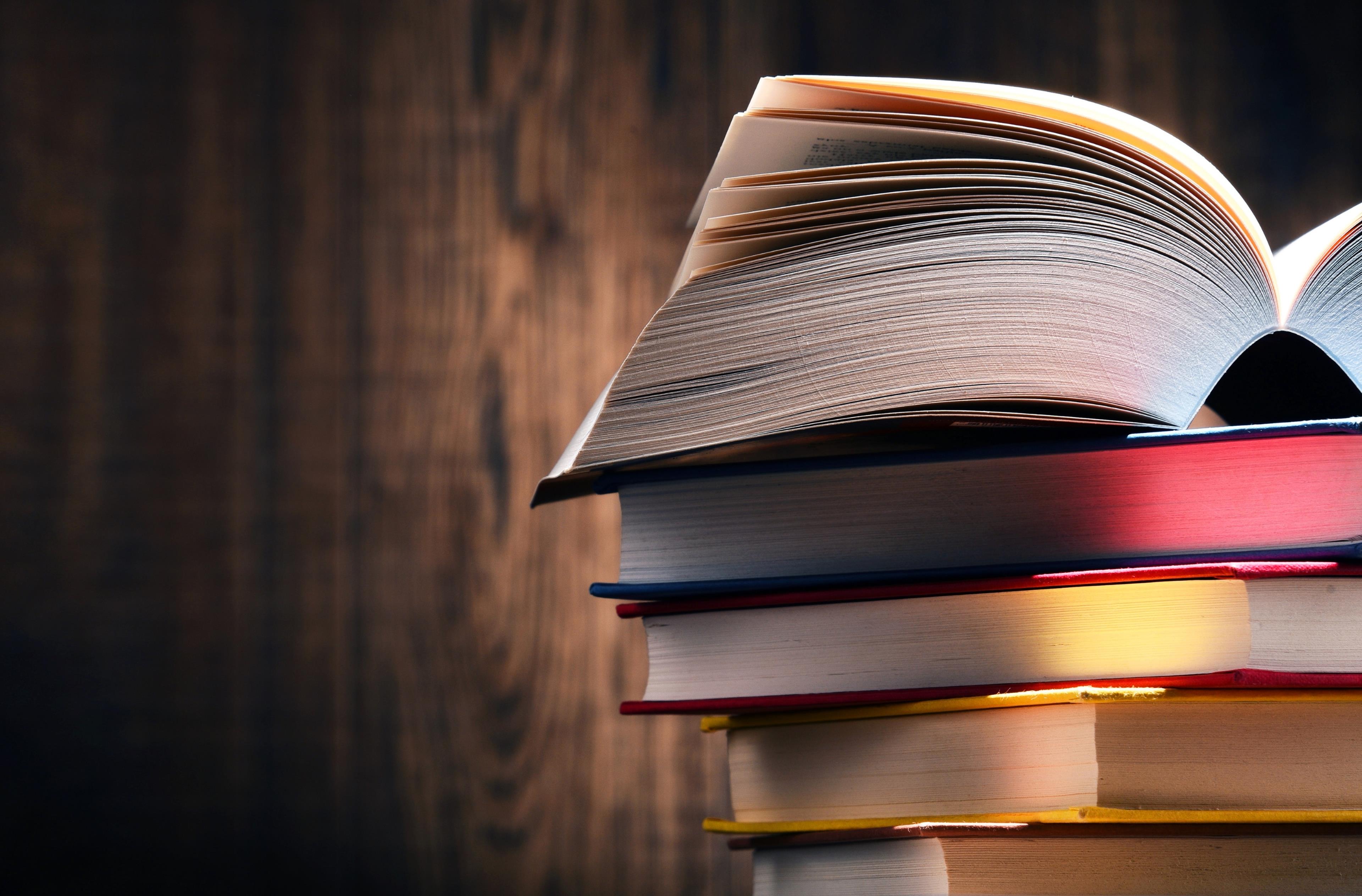 Libri accatastati l'uno sull'altro su uno sfondo legno 