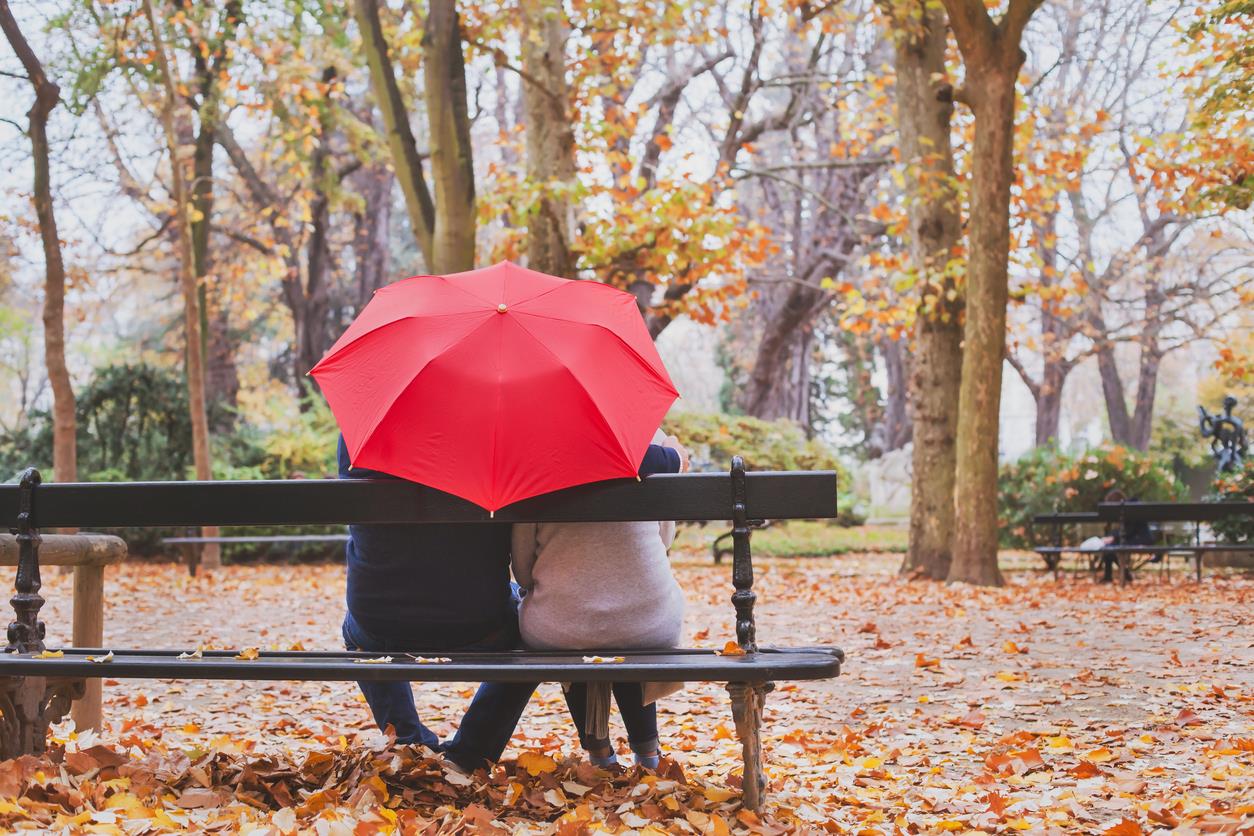 Coppia seduta su una panchina sotto l'ombrello
