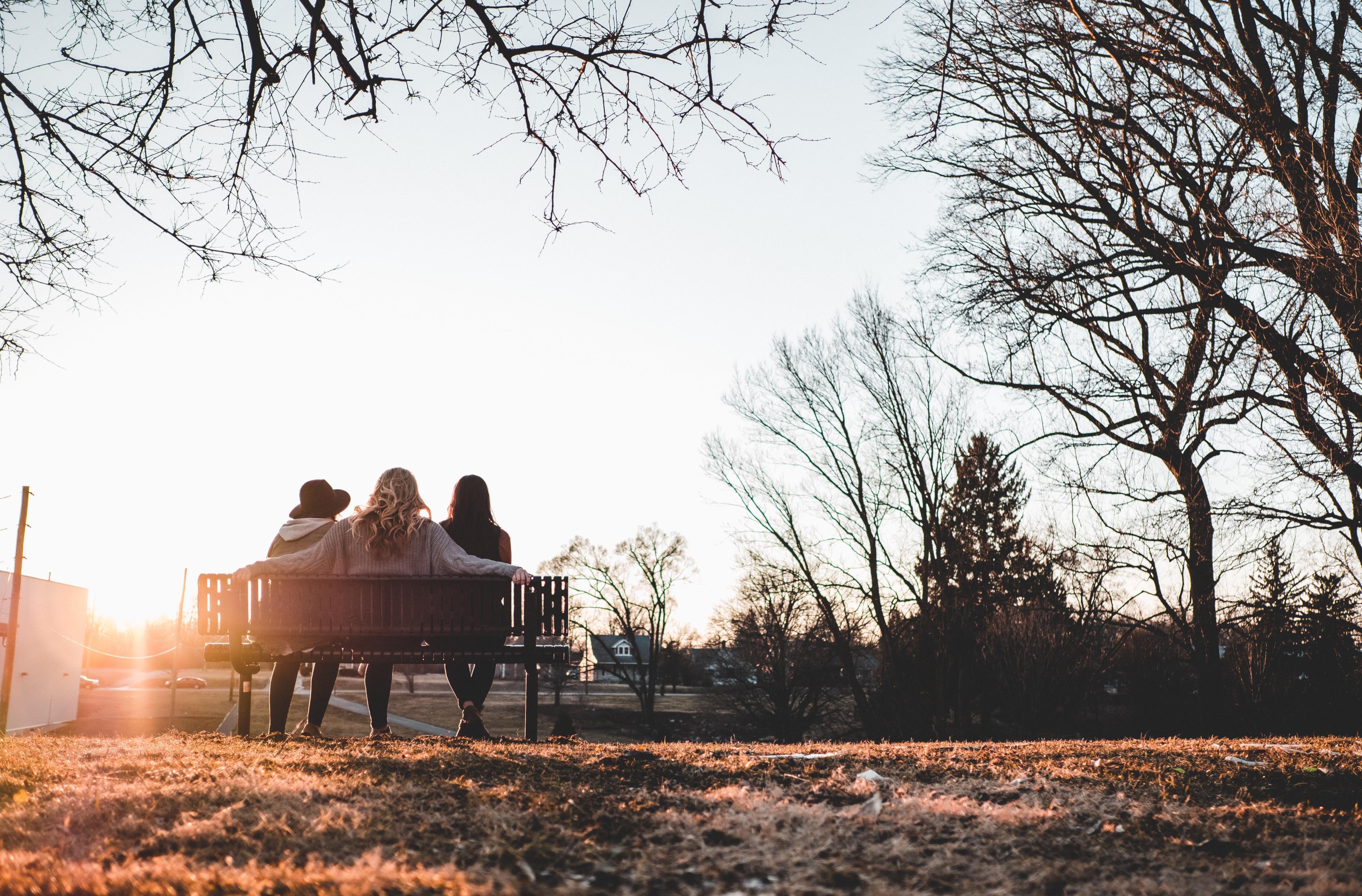 Tre amiche sedute su una panchina al tramonto