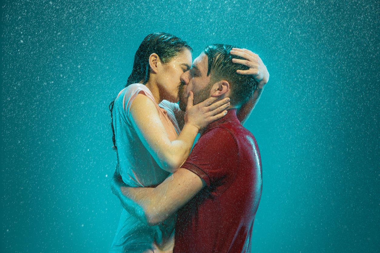 Un uomo e una donna si baciano sotto la pioggia