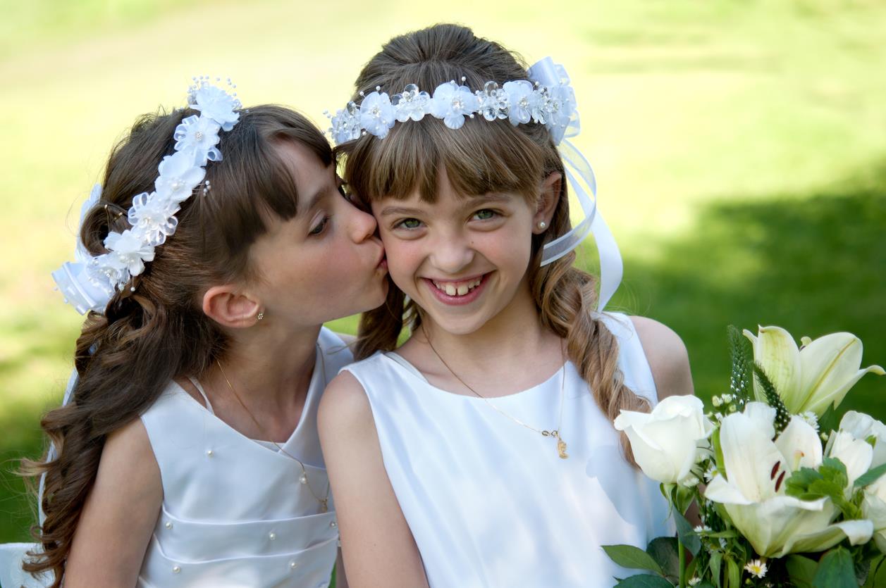 Due bambine vestite da Prima Comunione si abbracciano