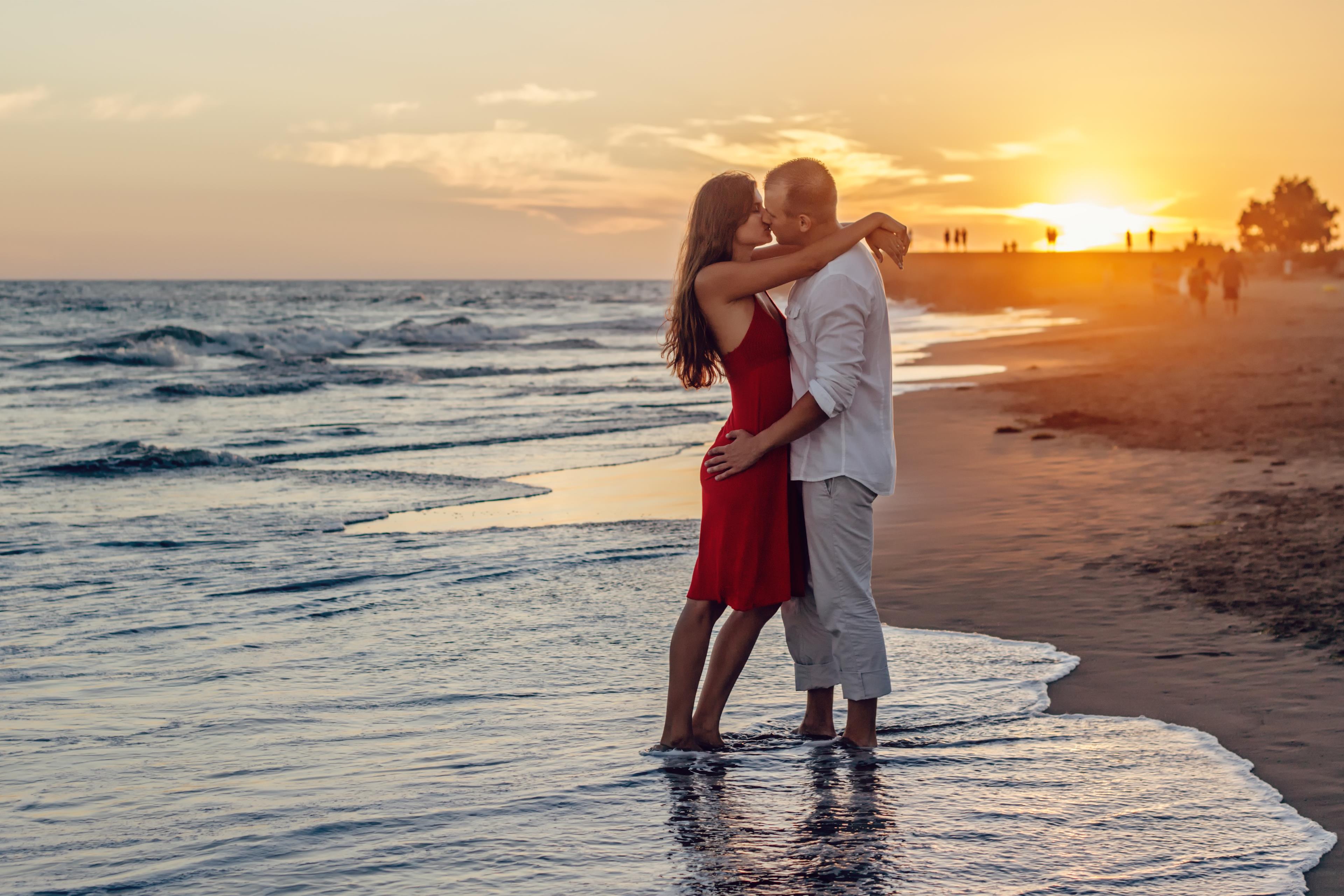 Coppia che si bacia sulla spiaggia al tramonto
