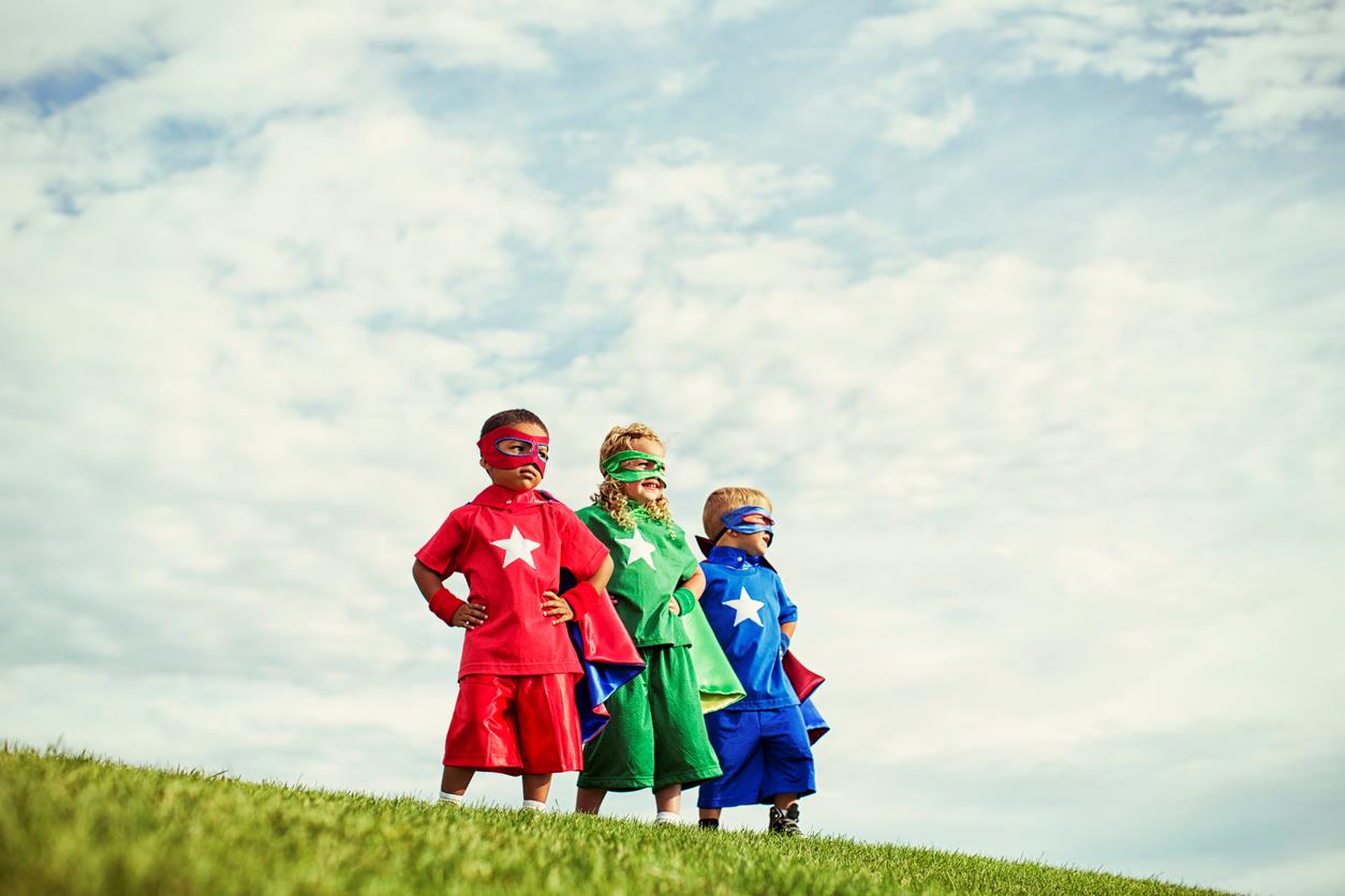 Tre bambini su una collina vestiti da supereroi