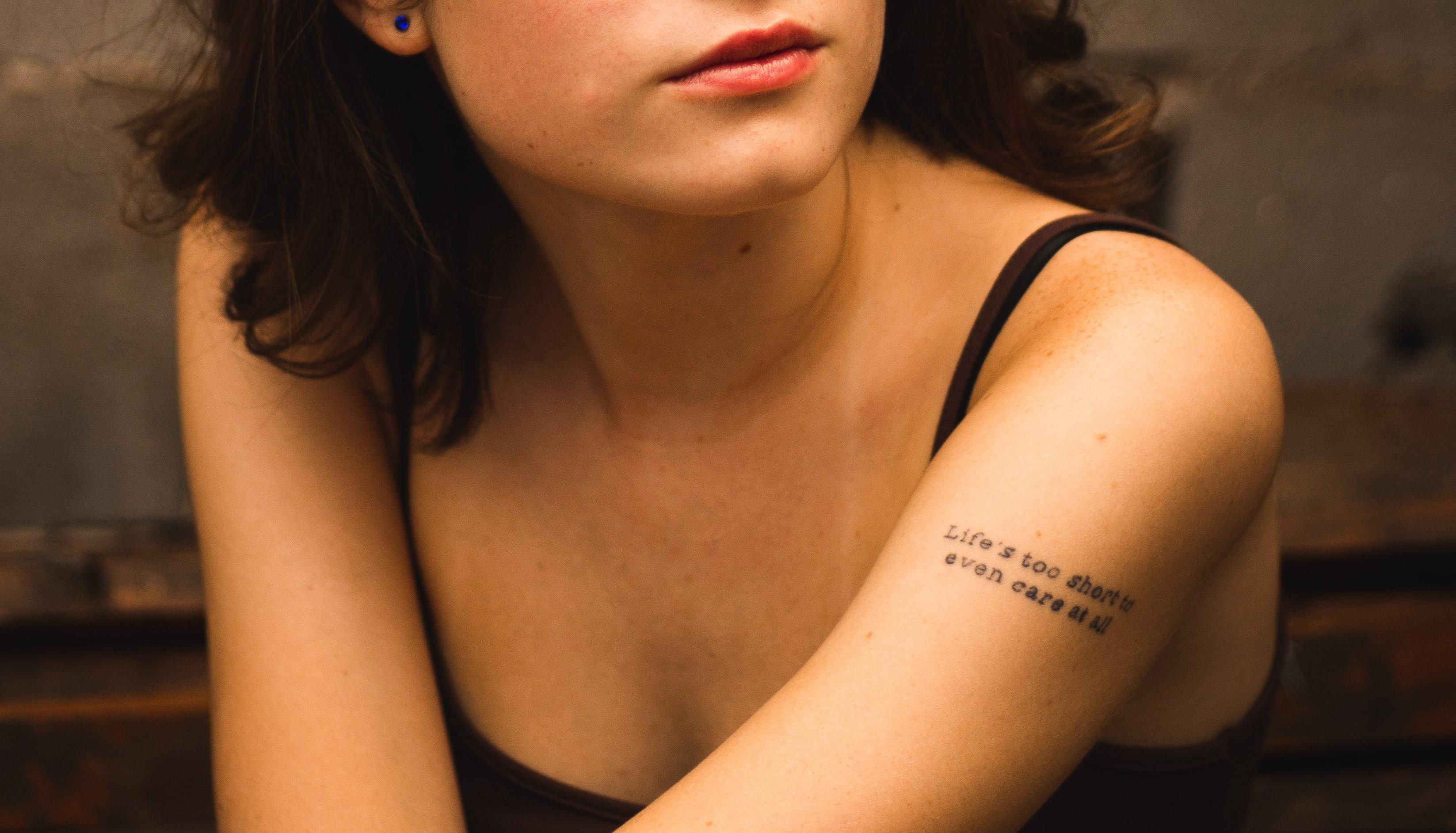 Donna con tatuaggio da braccio "Life is too short to even care"
