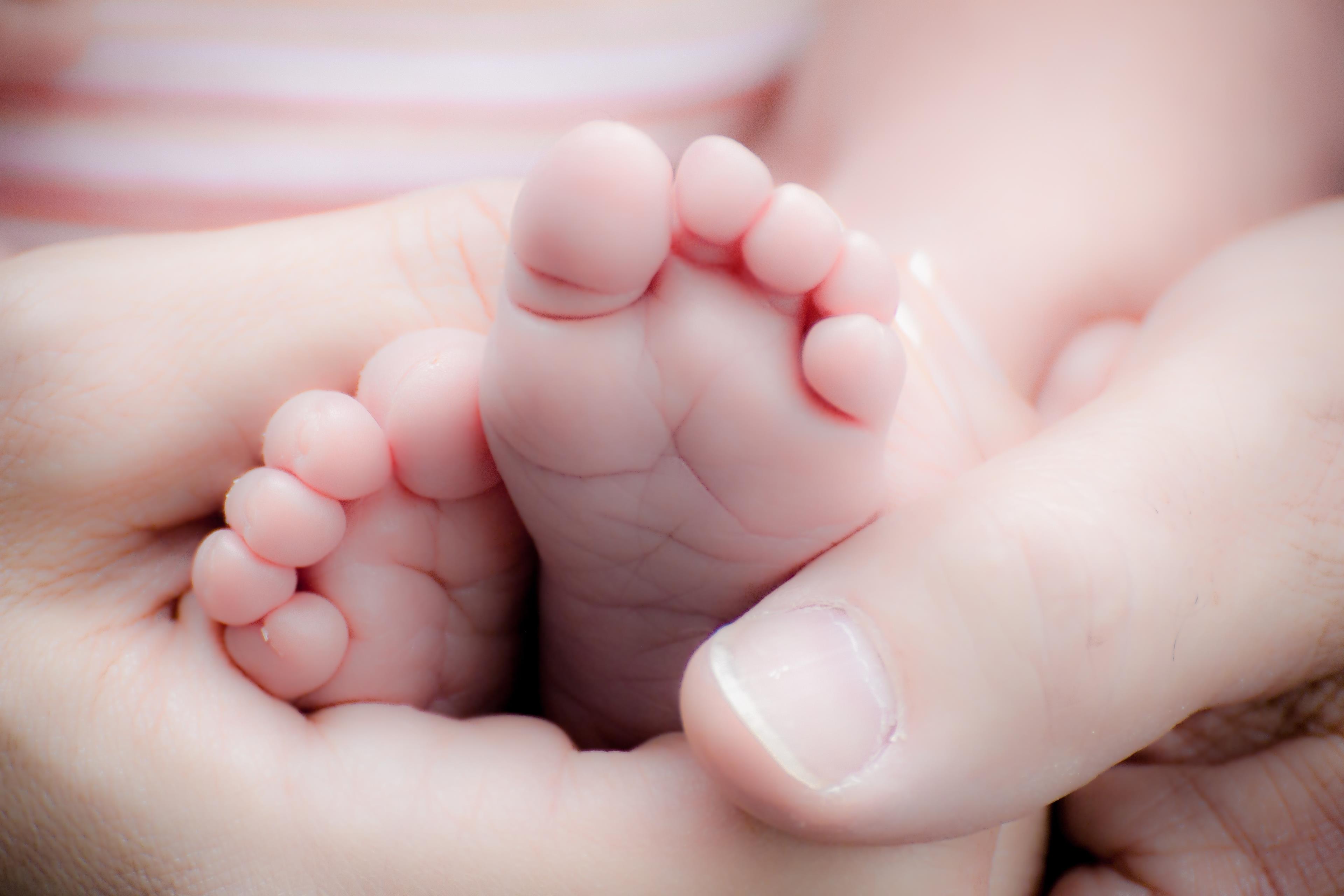 Mani di uomo che tengono i piedi di un neonato