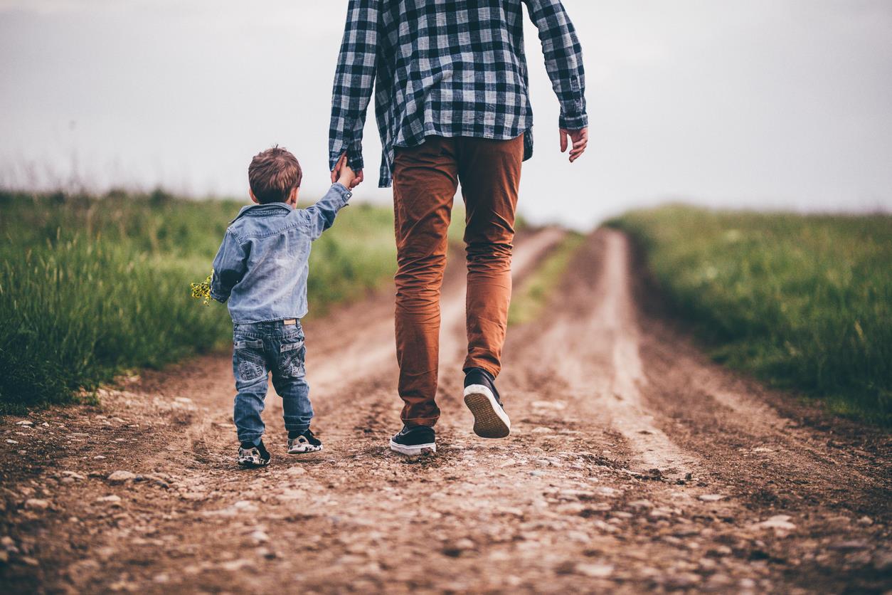Un padre cammina tenendo per mano suo figlio