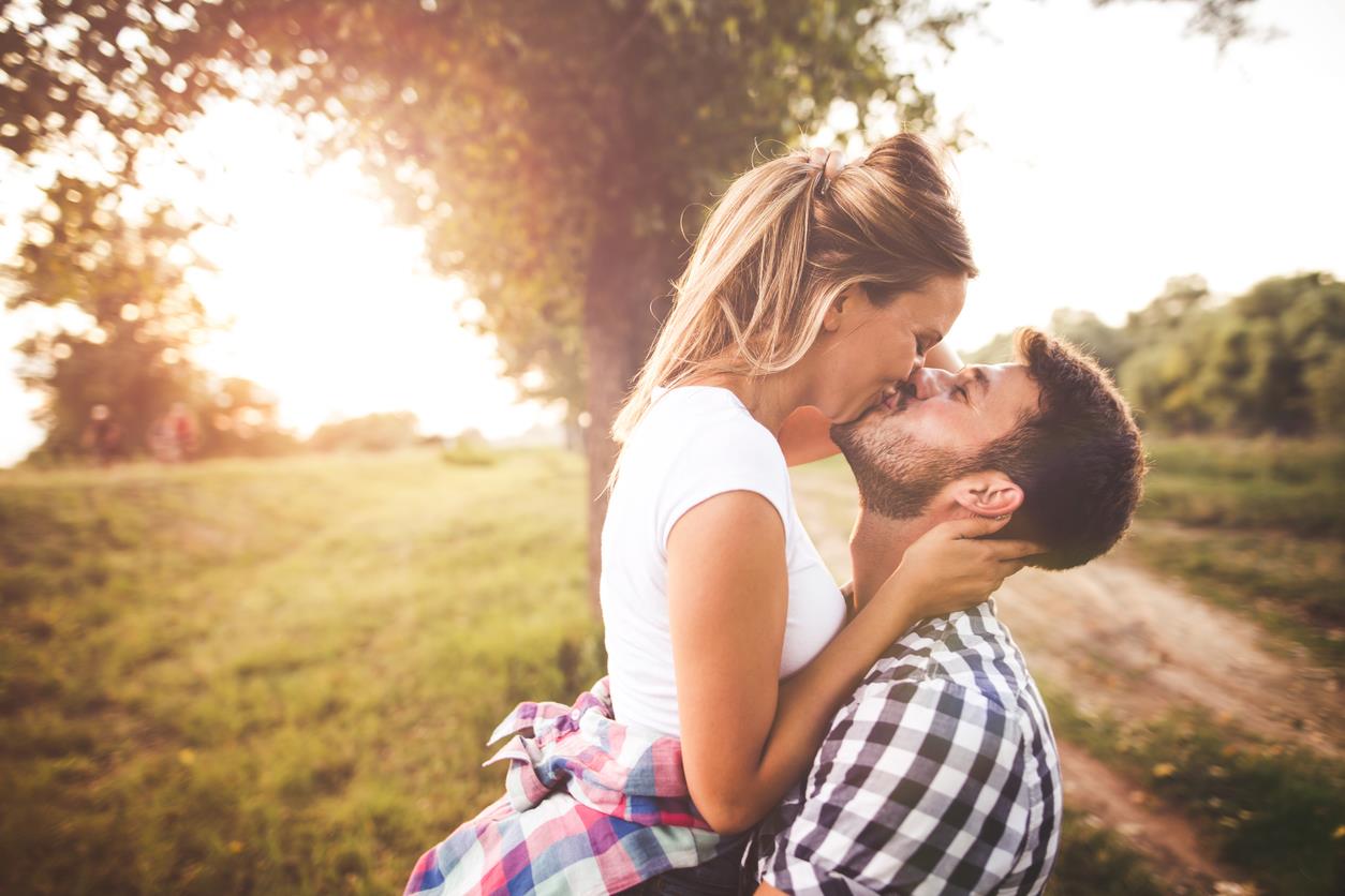 Una ragazza e un ragazzo si baciano su un sentiero di campagna