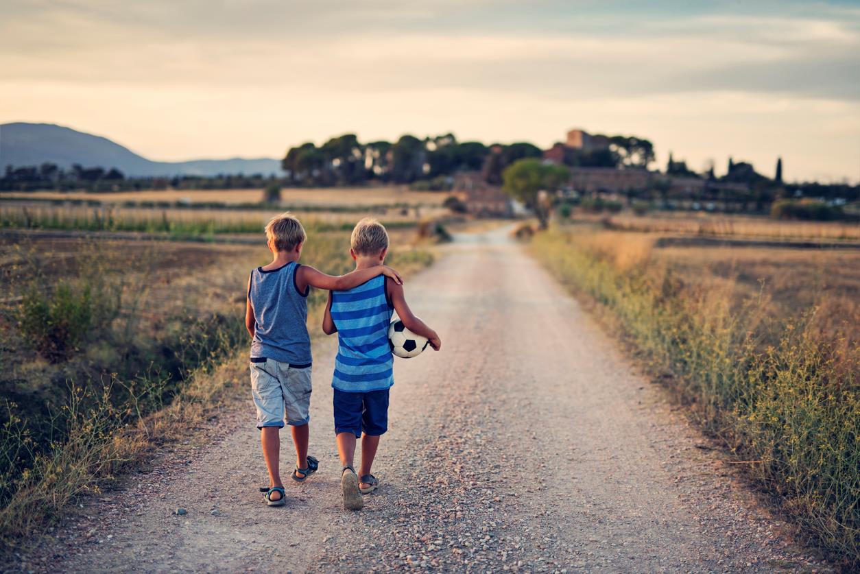 Due bambini camminano lungo una strada di campagna