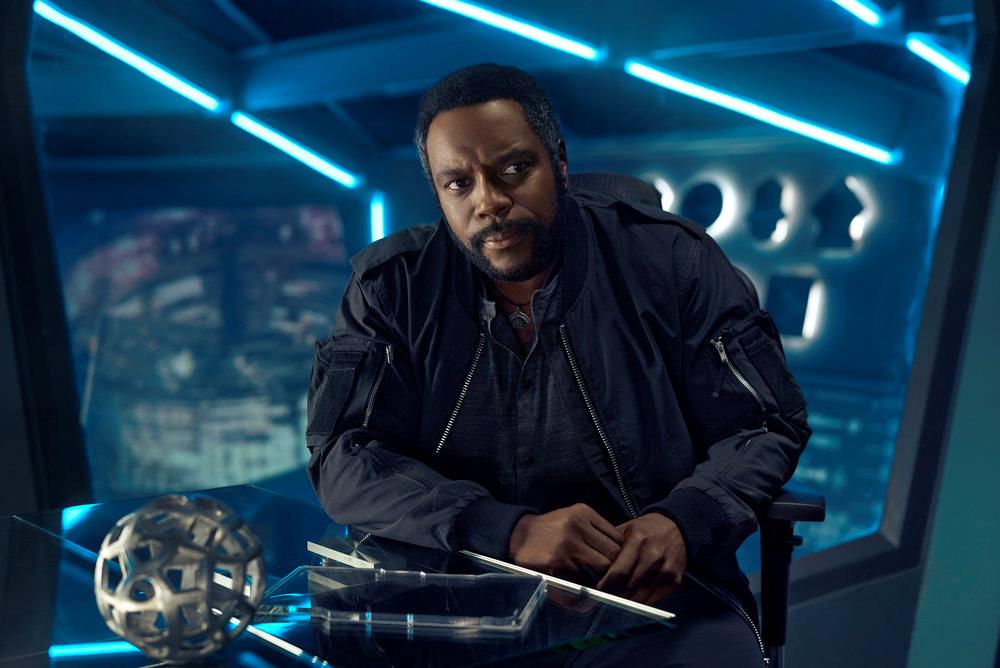 Mezzobusto di Chad Coleman nei panni di Fred Johnson, seduto a una scrivania