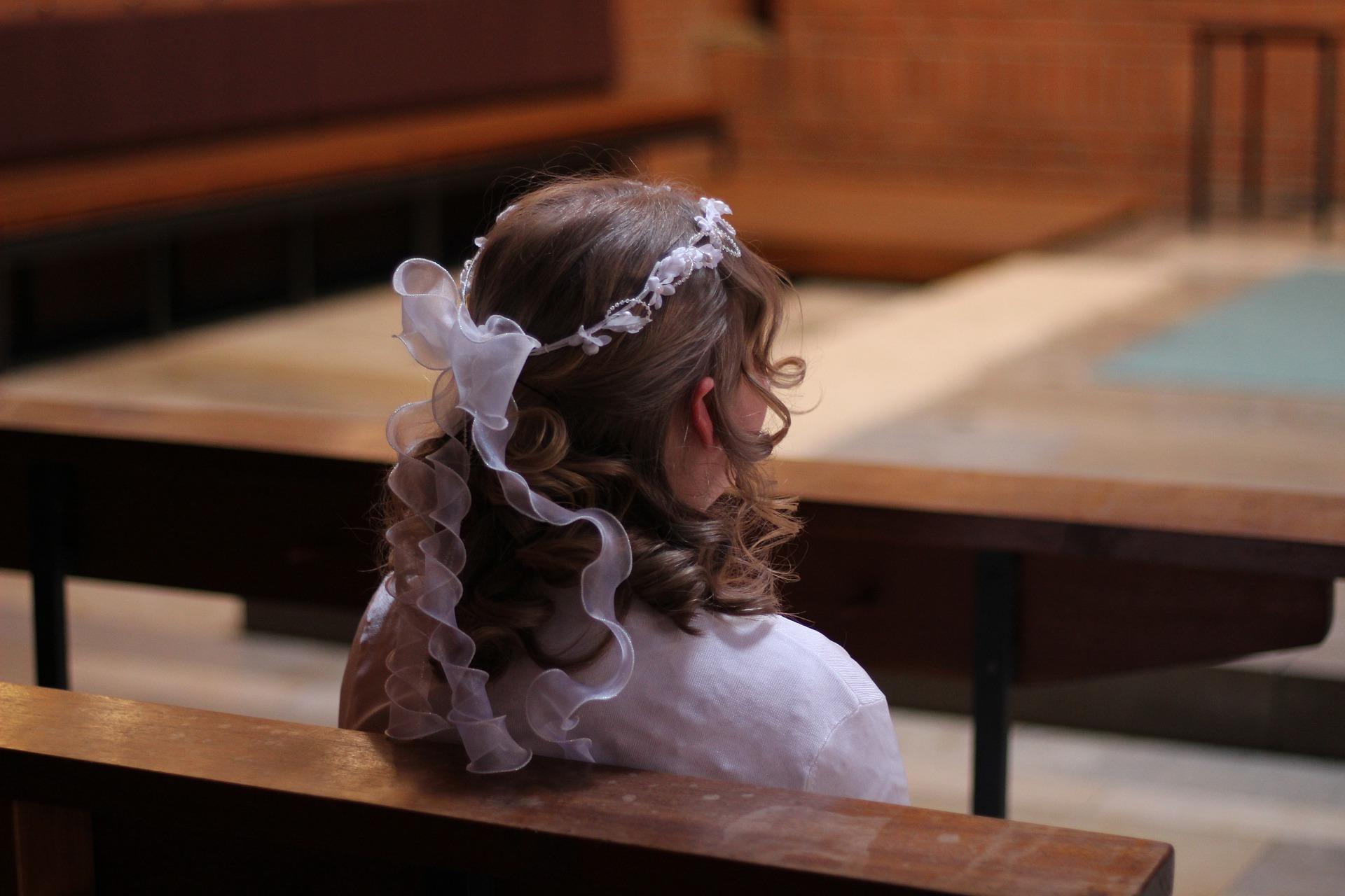 Bambina seduta in chiesa per la Santa Cresima